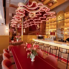 Eleganckie restauracje Kołobrzeg: czerwony stół, różowe fotele i bar z alkoholem.