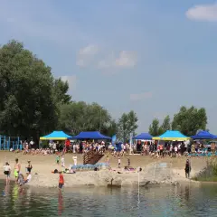 Ludzie odpoczywają nad wodą, pod namiotami odbywają się zawody. To piękne jeziora na Podkarpaciu w słoneczny dzień.