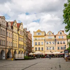 Kolorowe kamienice na rynku, kawiarniane stoliki i drzewa tworzą urokliwy widok. To idealne miejsce, by odkrywać **Jelenia Góra atrakcje**.