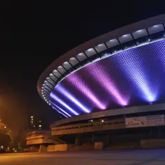 Nocne atrakcje w: Katowice. Spodek rozświetlony fioletowo-niebieskim światłem, nocą.