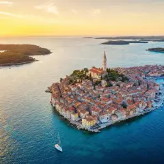 Malownicze miasteczko Rovinj w Chorwacji o zachodzie słońca. Dachy domów i kościół św. Eufemii lśnią w złotym świetle.