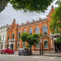 Kamienice w Radomiu, w tym Bank Polski, to ciekawe atrakcje. Dwa samochody stoją przed budynkami.