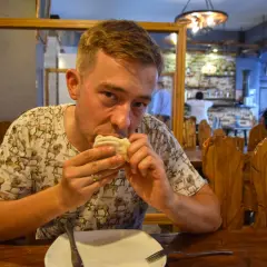 Mężczyzna je pierożki, delektując się smakami kuchni gruzińskiej w przytulnej restauracji.
