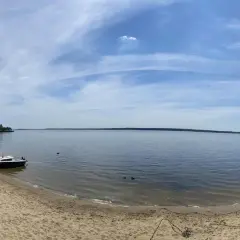 Piękny dzień nad jeziorami opolskimi. Piaszczysta plaża, spokojna woda i błękitne niebo zapraszają do wypoczynku.