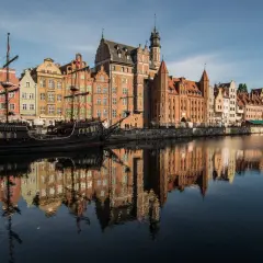 Gdańsk atrakcje: zabytkowy żaglowiec cumuje przy nabrzeżu Motławy, obok kolorowych kamieniczek.