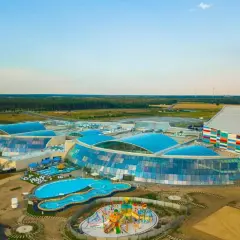 Nowoczesny kompleks z basenami i zjeżdżalniami, największy park wodny w Polsce, otoczony zielenią.