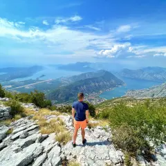 Widok z góry na Zatokę Kotorską, z turystą podziwiającym panoramę. Park narodowy Lovćen oferuje zapierające dech w piersiach krajobrazy.