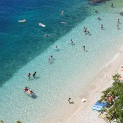Słoneczne rijeka plaże z turkusową wodą. Ludzie kąpią się, opalają na kamienistej plaży i relaksują na materacach.