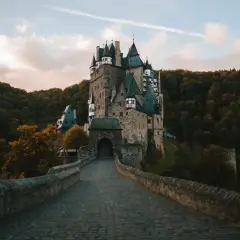 Zamek Eltz, jedna z najpiękniejszych atrakcji Niemiec, otoczony jesiennym lasem. Kamienny most prowadzi do bramy.