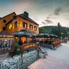 Restauracja "Niebo w Gębie" w Karpaczu oferuje pyszne jedzenie. Widać tu menu i stoliki na zewnątrz.