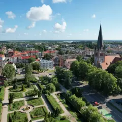 Widok na miasto z lotu ptaka, z dominującą wieżą kościoła i zielonym parkiem. Szczecinek atrakcje zachęcają do spacerów.
