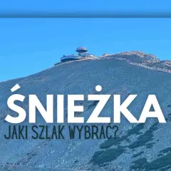 Szlak na Śnieżkę. Widok na górę z budynkami na szczycie i turystami na ścieżkach.