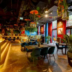 Złota małpa wita w jednej z klimatycznych restauracji Warszawa. Wnętrze pełne zieleni, czerwonych zasłon i egzotycznych dekoracji.