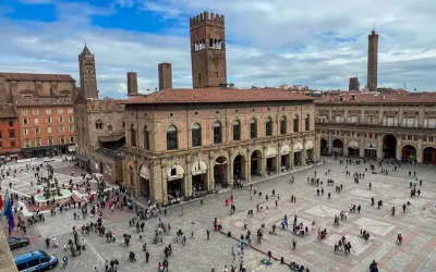 Tłum ludzi na Piazza Maggiore w Bolonii, podziwiający zabytkowe budynki i wieże. To serce miasta i jego główne bolonia atrakcje.