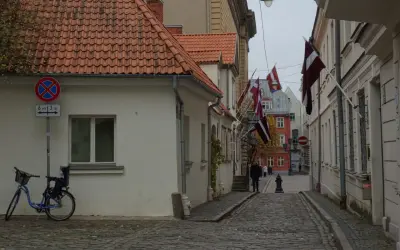 Urokliwa uliczka w Rydze, z łotewskimi flagami i brukowaną nawierzchnią. Idealne miejsce, by poczuć atmosferę miasta i odkryć, co zobaczyć w Rydze.