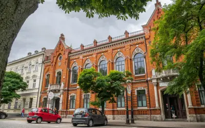 Kamienice w Radomiu, w tym Bank Polski, to ciekawe atrakcje. Dwa samochody stoją przed budynkami.