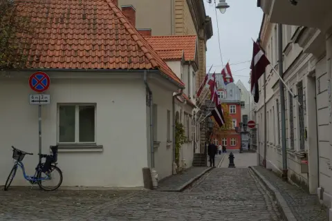 Urokliwa uliczka w Rydze, z łotewskimi flagami i brukowaną nawierzchnią. Idealne miejsce, by poczuć atmosferę miasta i odkryć, co zobaczyć w Rydze.