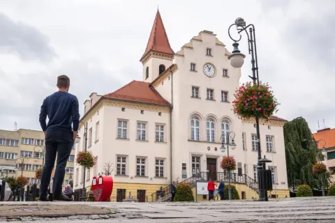 Mężczyzna patrzy na ratusz w Trzebnicy, jedno z wielu urokliwych miejsc i atrakcji tego miasta.