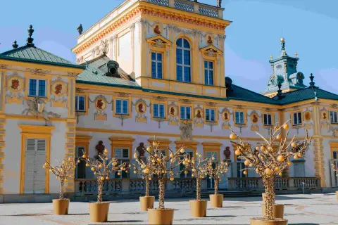 Barokowy pałac, jeden z pięknych muzeów w Polsce, z ozdobnymi drzewkami w donicach przed fasadą.