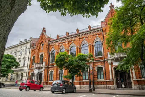 Kamienice w Radomiu, w tym Bank Polski, to ciekawe atrakcje. Dwa samochody stoją przed budynkami.