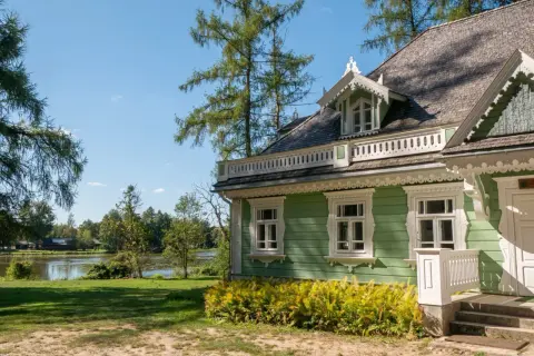 Zielony, drewniany dom z werandą i ozdobnymi detalami, nad jeziorem. Idealne miejsce na białowieża plan zwiedzania.