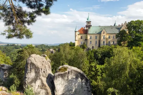 Zamek na skale, otoczony zielenią, to jedna z malowniczych atrakcji w Czechach. Widok na skalne formacje i krajobraz.