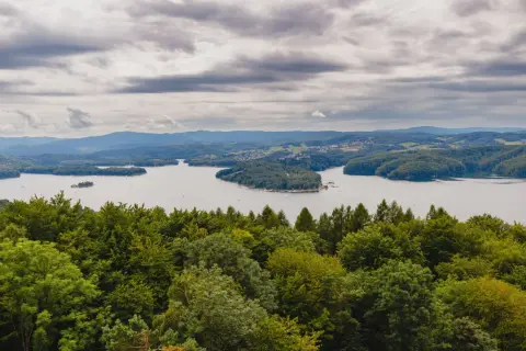Widok na Jezioro Solińskie zalesione wzgórza i chmury. Solina atrakcje to raj dla miłośników przyrody i spokoju.