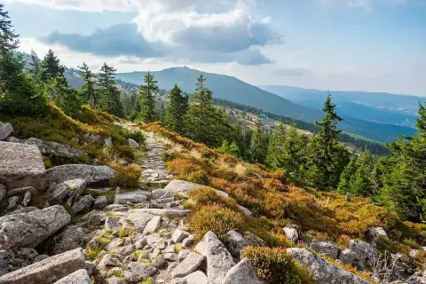 Kamienista ścieżka w górach Karkonoszach, w okolicy Szklarskiej Poręby. W oddali widać kolejne pasma górskie.