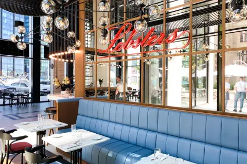 Eleganckie restauracje w Warszawie z niebieskimi kanapami i neonowym napisem "Lobsters".