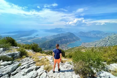 Widok z góry na Zatokę Kotorską, z turystą podziwiającym panoramę. Park narodowy Lovćen oferuje zapierające dech w piersiach krajobrazy.