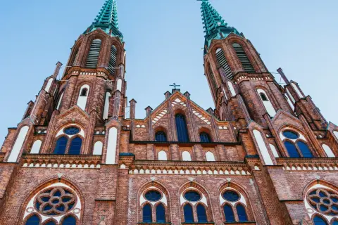 Imponująca ceglana bazylika z dwiema strzelistymi wieżami, ozdobiona oknami i detalami architektonicznymi. Jeden z najpiękniejszych kościołów w Polsce.