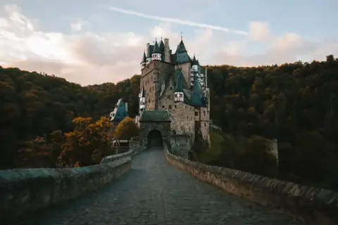 Zamek Eltz, jedna z najpiękniejszych atrakcji Niemiec, otoczony jesiennym lasem. Kamienny most prowadzi do bramy.