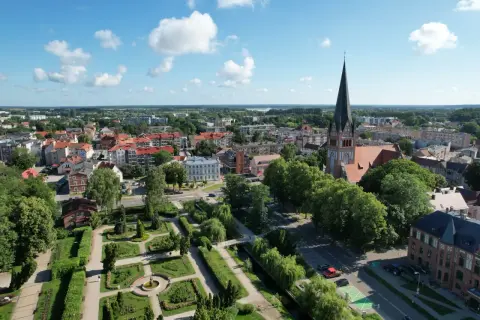 Widok na miasto z lotu ptaka, z dominującą wieżą kościoła i zielonym parkiem. Szczecinek atrakcje zachęcają do spacerów.