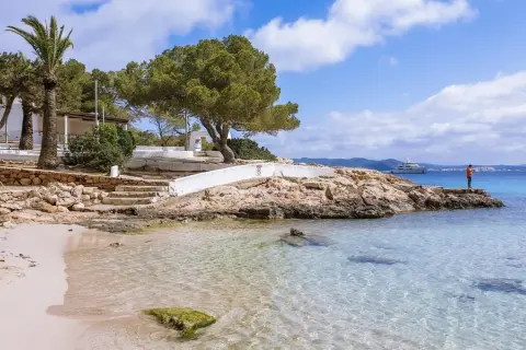 Piękna plaża na Ibizie, idealne miejsce, by zobaczyć błękitne morze i poczuć słońce. Na horyzoncie luksusowy jacht.