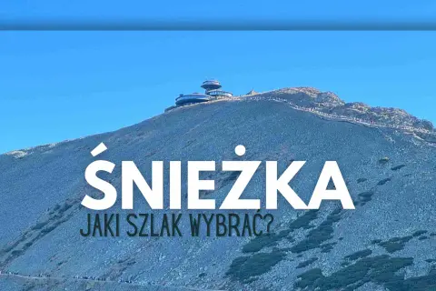 Szlak na Śnieżkę. Widok na górę z budynkami na szczycie i turystami na ścieżkach.