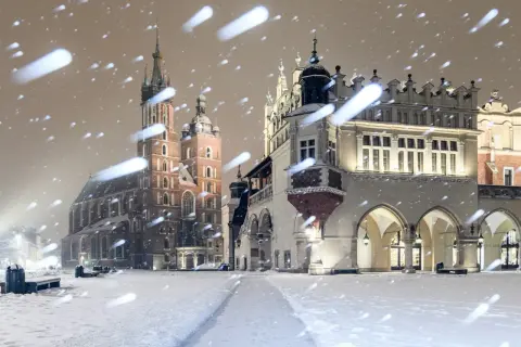 Magiczny krakow zima. Rynek Główny w śnieżnej scenerii, z Kościołem Mariackim i Sukiennicami w tle, podczas nocnych opadów śniegu.