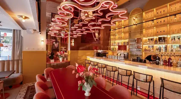Eleganckie restauracje Kołobrzeg: czerwony stół, różowe fotele i bar z alkoholem.