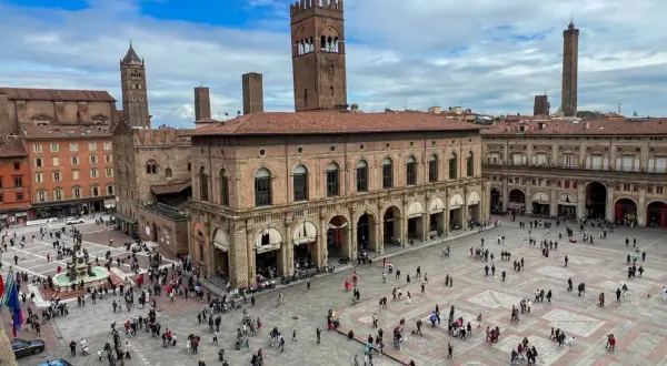Tłum ludzi na Piazza Maggiore w Bolonii, podziwiający zabytkowe budynki i wieże. To serce miasta i jego główne bolonia atrakcje.