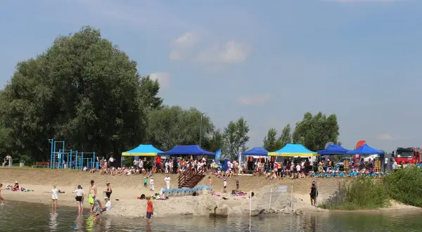 Ludzie odpoczywają nad wodą, pod namiotami odbywają się zawody. To piękne jeziora na Podkarpaciu w słoneczny dzień.
