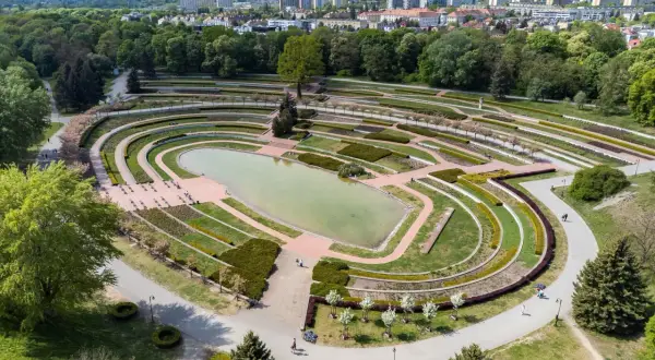 Widok z lotu ptaka na park cytadela z jeziorem, tarasami i alejkami. W tle widać miasto.