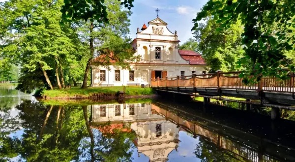 Pałac z mostkiem i odbiciem w wodzie. Wspaniałe zwierzyniec atrakcje czekają na zwiedzających w otoczeniu zieleni.