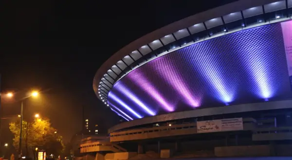 Nocne atrakcje w: Katowice. Spodek rozświetlony fioletowo-niebieskim światłem, nocą.
