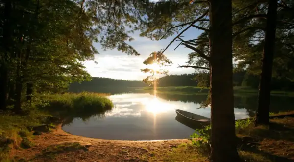 Zachód słońca nad jeziorem, łódka przy brzegu, idealne plaże na Mazurach.