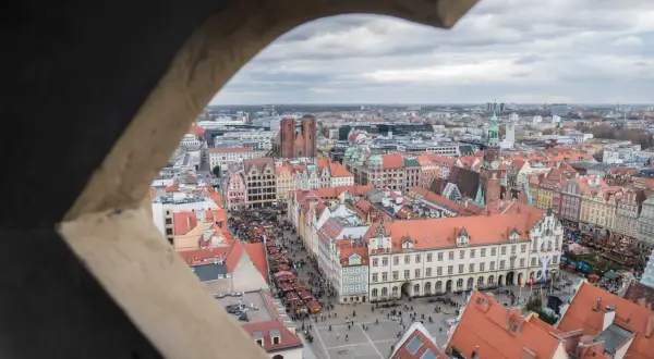 Widok z wieży widokowej we Wrocławiu na Rynek i Ostrów Tumski. Widać kolorowe kamienice, targ i katedrę.