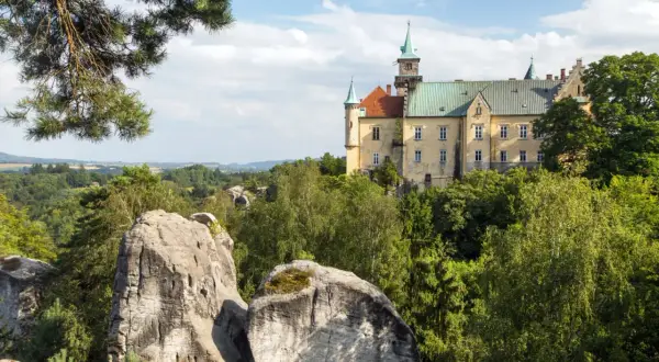 Zamek na skale, otoczony zielenią, to jedna z malowniczych atrakcji w Czechach. Widok na skalne formacje i krajobraz.