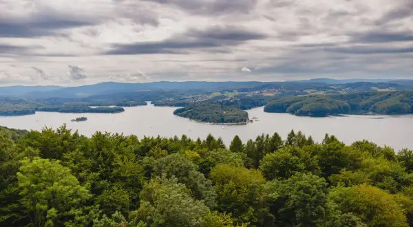 Widok na Jezioro Solińskie zalesione wzgórza i chmury. Solina atrakcje to raj dla miłośników przyrody i spokoju.