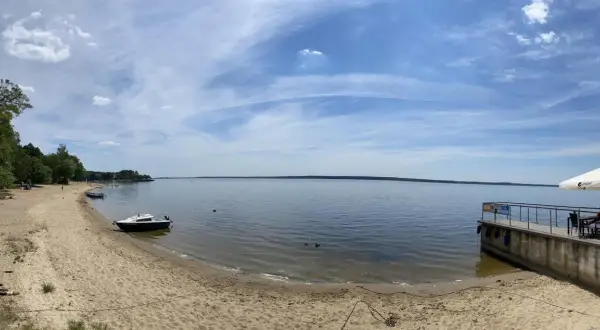 Piękny dzień nad jeziorami opolskimi. Piaszczysta plaża, spokojna woda i błękitne niebo zapraszają do wypoczynku.