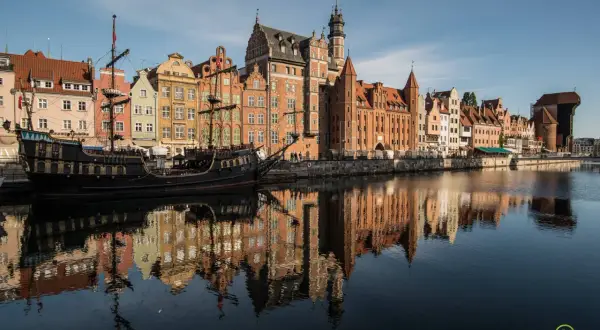 Gdańsk atrakcje: zabytkowy żaglowiec cumuje przy nabrzeżu Motławy, obok kolorowych kamieniczek.