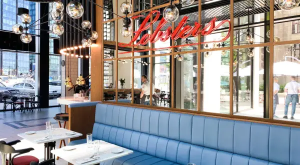 Eleganckie restauracje w Warszawie z niebieskimi kanapami i neonowym napisem "Lobsters".