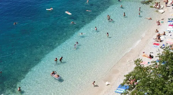 Słoneczne rijeka plaże z turkusową wodą. Ludzie kąpią się, opalają na kamienistej plaży i relaksują na materacach.